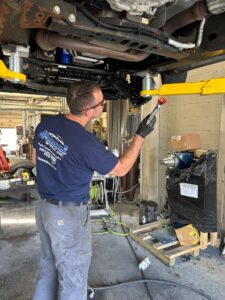 Technician applying undercoating to the undercarriage of a car for rust protection